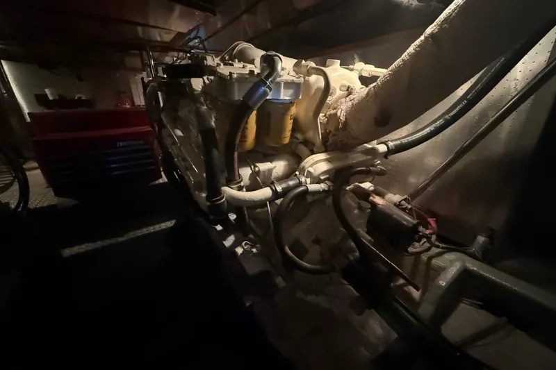 Slide: The Image of Engine room of a 1987 PT Sundeck boat, showcasing mechanical components and wiring. - 62