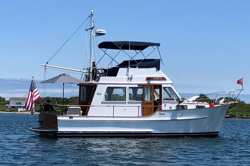 The Image of 1986 Island Gypsy 32 Sedan Trawler on calm water, featuring classic design and American flag. - 0