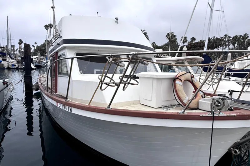 The Image of 1974 Skookum 34 boat docked in marina, featuring classic design and life preserver. - 1