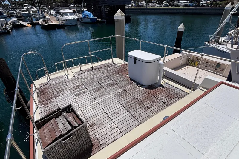Slide: The Image of Deck of 1974 Skookum 34 boat at marina, featuring wooden flooring and storage box. - 12