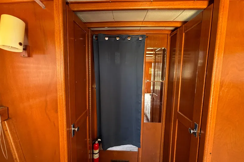 Slide: The Image of Interior of a 1974 Skookum 34 boat with wooden paneling and a blue curtain. - 19