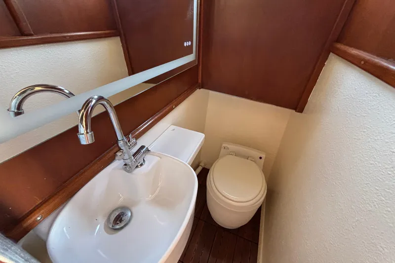 Slide: The Image of Compact bathroom in a 1974 Skookum 34 boat, featuring a sink and toilet. - 25