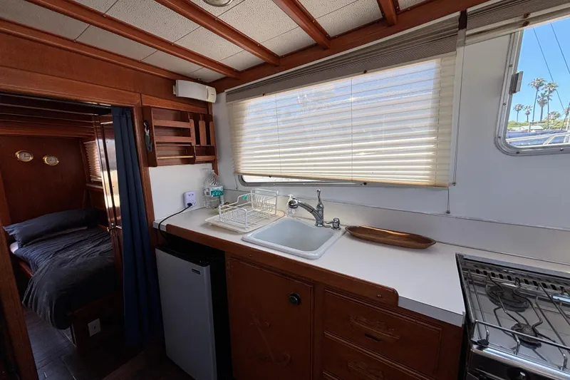 Slide: The Image of 1974 Skookum 34 boat interior with kitchenette, sink, and cozy sleeping area. - 31