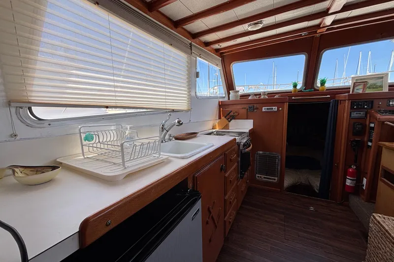 Slide: The Image of Interior of a 1974 Skookum 34 boat featuring a compact kitchen with wooden cabinetry. - 32