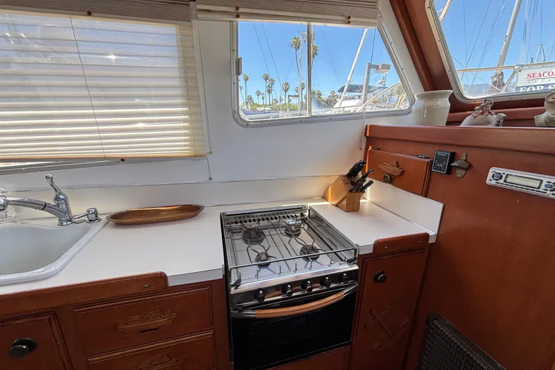 Slide: The Image of 1974 Skookum 34 yacht kitchen with stove, sink, and wooden cabinetry. - 33