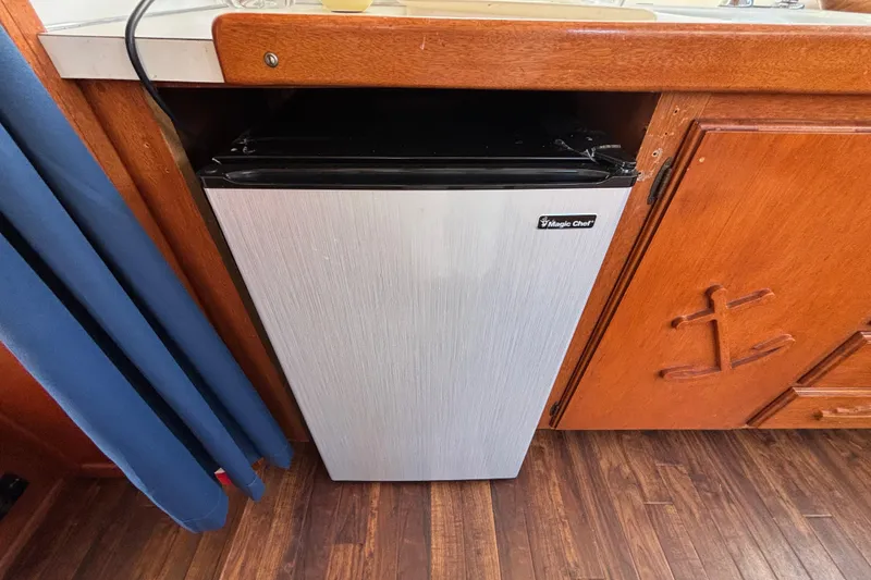 Slide: The Image of Compact Magic Chef fridge in a 1974 Skookum 34 boat kitchen, with wooden cabinetry. - 34