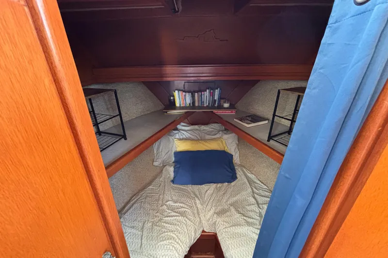 Slide: The Image of Cozy cabin interior of 1974 Skookum 34 sailboat with bed, books, and shelves. - 35