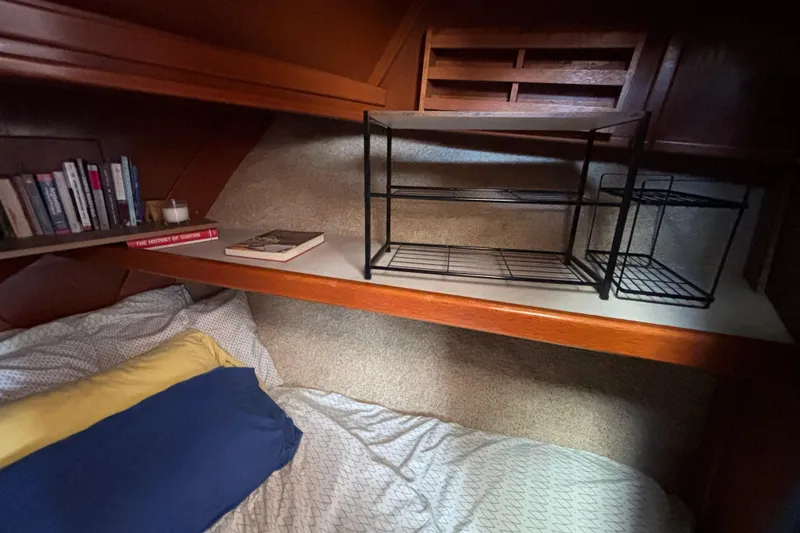 Slide: The Image of Cozy cabin interior of a 1974 Skookum 34 sailboat with books and bedding. - 36