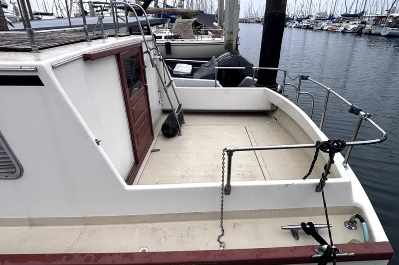 Slide: The Image of 1974 Skookum 34 boat docked at marina, featuring spacious deck and railing. - 4