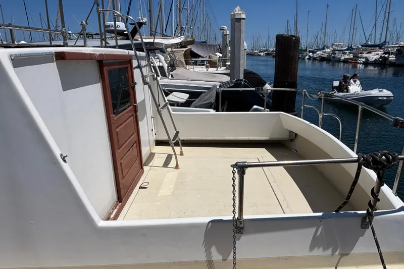 Slide: The Image of 1974 Skookum 34 boat docked at marina, featuring open deck and wooden door. - 6