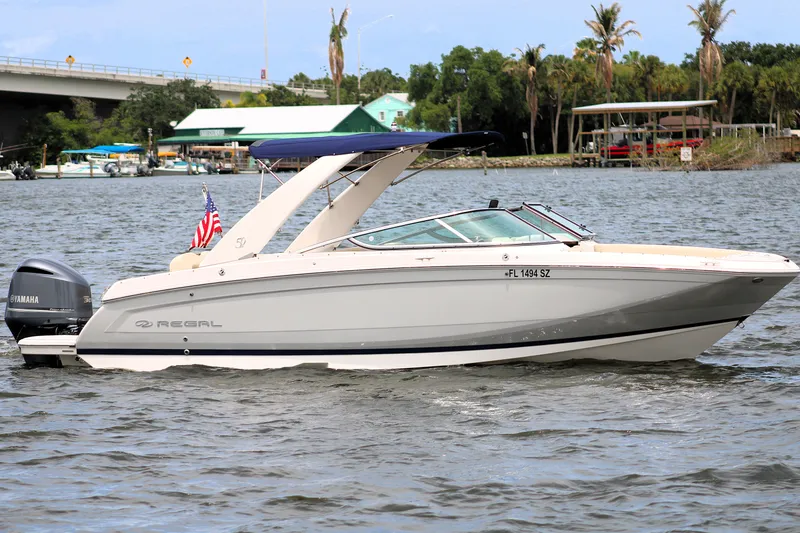 Slide: The Image of 2021 Regal 26 OBX boat cruising on a river with a Yamaha outboard motor. - 2
