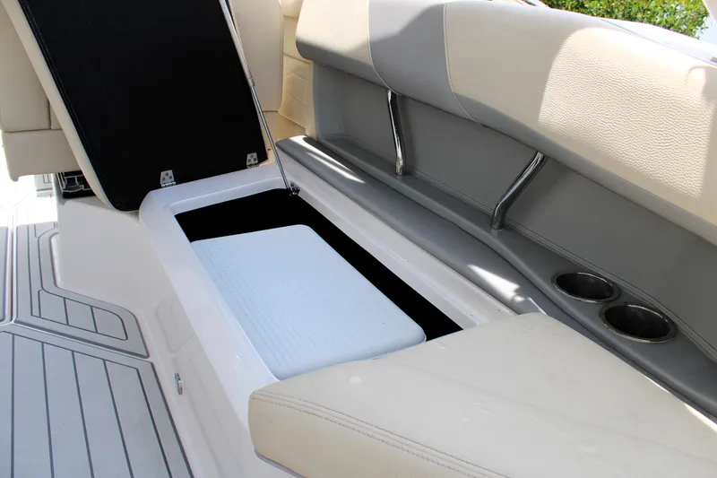 Slide: The Image of 2021 Regal 26 OBX boat interior storage compartment with open lid and cup holders. - 26
