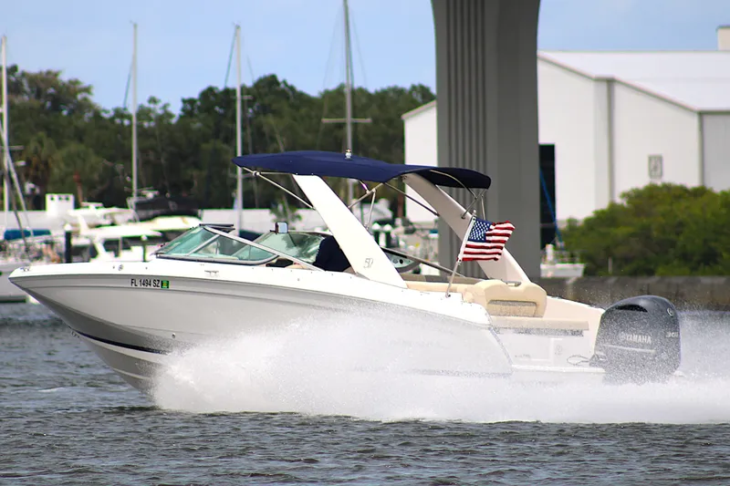 Slide: The Image of 2021 Regal 26 OBX boat cruising on water with American flag. - 46