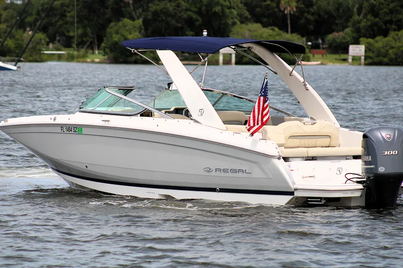Slide: The Image of 2021 Regal 26 OBX boat cruising on a lake with an American flag. - 7