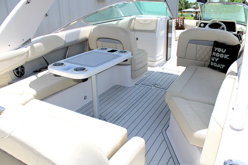Slide: The Image of 2021 Regal 26 OBX boat interior with beige seating and table, featuring a decorative pillow. - 9