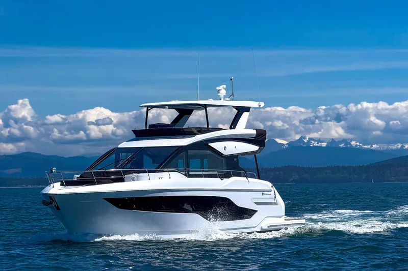 Slide: The Image of 2027 Cruisers Yachts 50 Fly cruising on a scenic, sunny day with mountains in the background. - 3