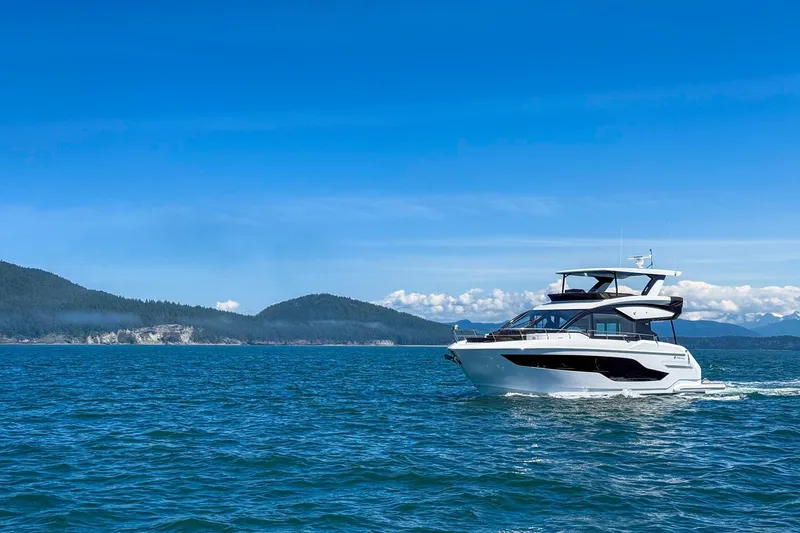 Slide: The Image of 2027 Cruisers Yachts 50 Fly cruising on blue ocean with scenic mountain backdrop. - 4