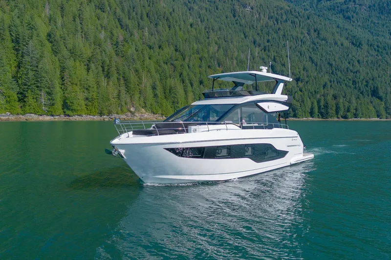 Slide: The Image of 2027 Cruisers Yachts 50 Fly navigating serene waters with lush forest backdrop. - 6