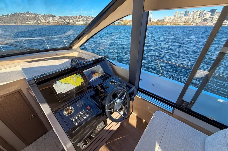 Slide: The Image of Cockpit view of 2027 Cruisers Yachts 50 Fly, featuring navigation controls and waterfront cityscape. - 26
