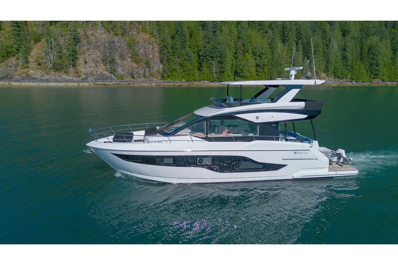 The Image of 2027 Cruisers Yachts 50 Fly cruising on a serene lake with forested backdrop. - 0
