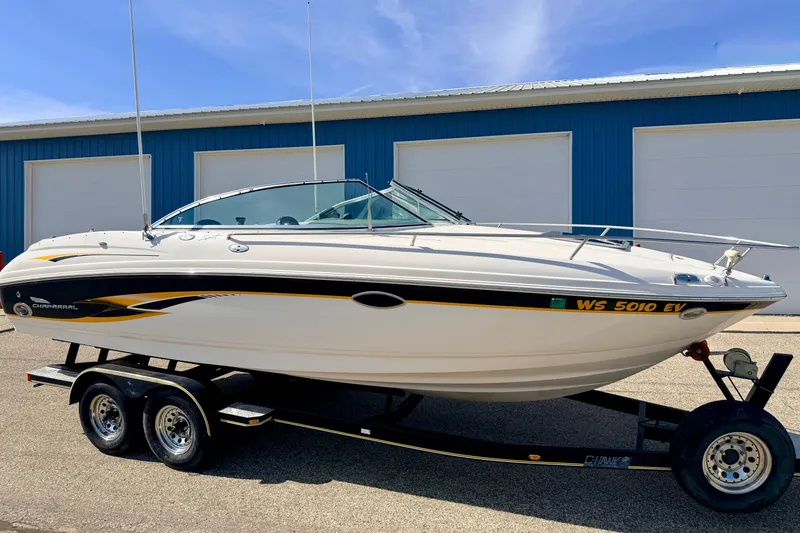 Slide: The Image of 2000 Chaparral 235 SSi boat on trailer, parked near blue storage units. - 2