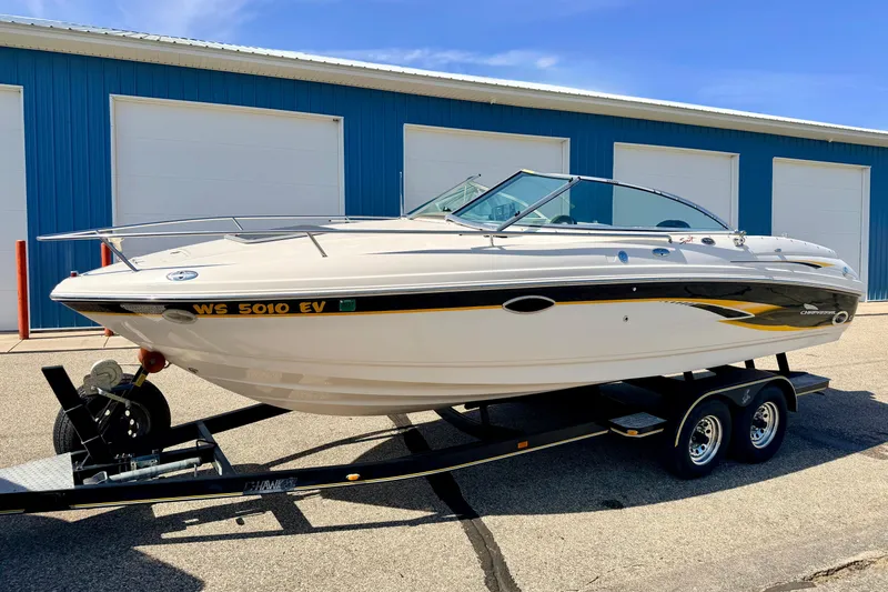 Slide: The Image of 2000 Chaparral 235 SSi boat on trailer, parked near blue storage units. - 3
