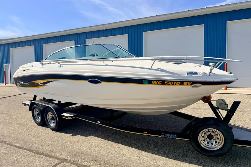 Slide: The Image of 2000 Chaparral 235 SSi boat on trailer, parked near blue warehouse. - 5