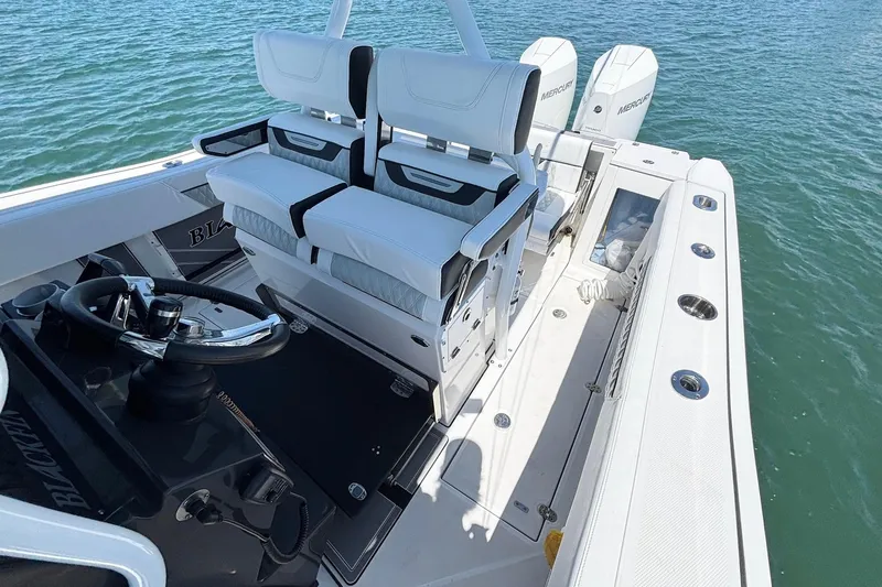 Slide: The Image of 2024 Blackfin 272 CC boat interior with dual seats and steering wheel on open water. - 15