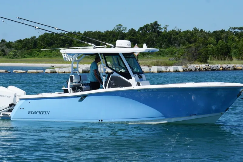 Slide: The Image of 2024 Blackfin 272 CC boat cruising on a sunny day near a rocky shoreline. - 4
