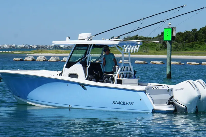 Slide: The Image of 2024 Blackfin 272 CC boat cruising on clear blue water near a shoreline. - 6