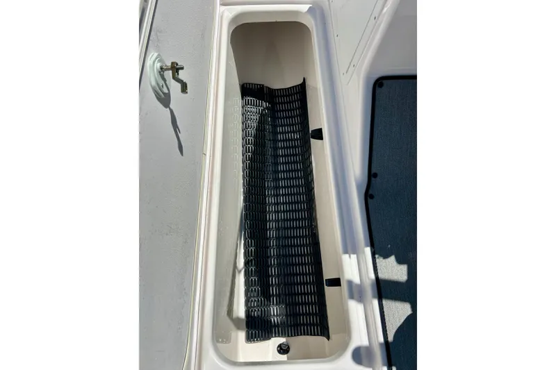 Slide: The Image of 2024 Yamaha Boats SX195 storage compartment with black mat inside. - 42