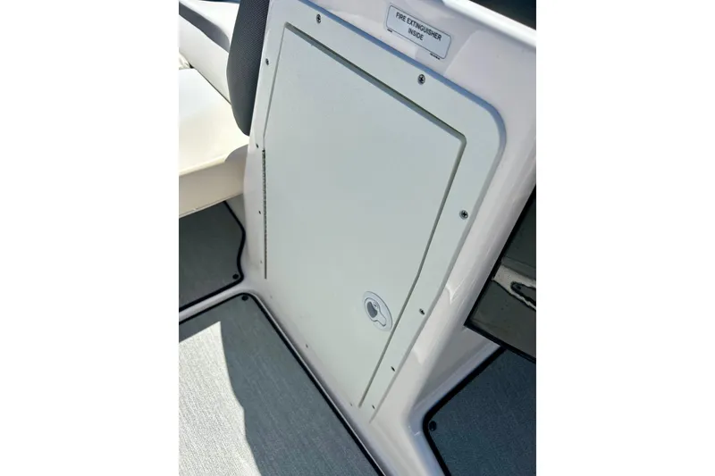 Slide: The Image of 2024 Yamaha Boats SX195 interior storage compartment with fire extinguisher label. - 51