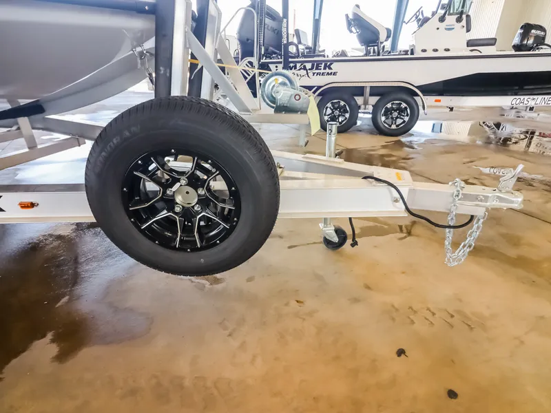 Slide: The Image of A boat trailer with a black wheel and chain, with another boat in the background. - 22