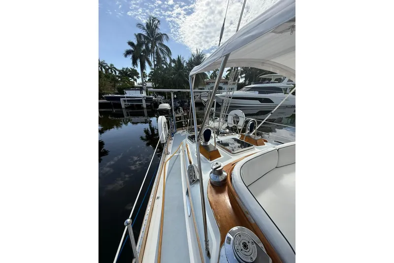 Slide: The Image of 1986 Little Harbor LH46 yacht deck with polished wood and white seating, docked near palm trees. - 24