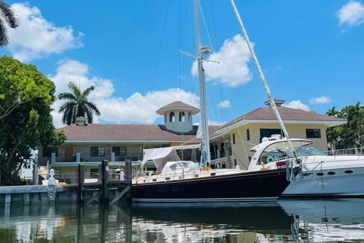 Slide: The Image of 1986 Little Harbor LH46 sailboat docked by waterfront homes under a clear blue sky. - 3
