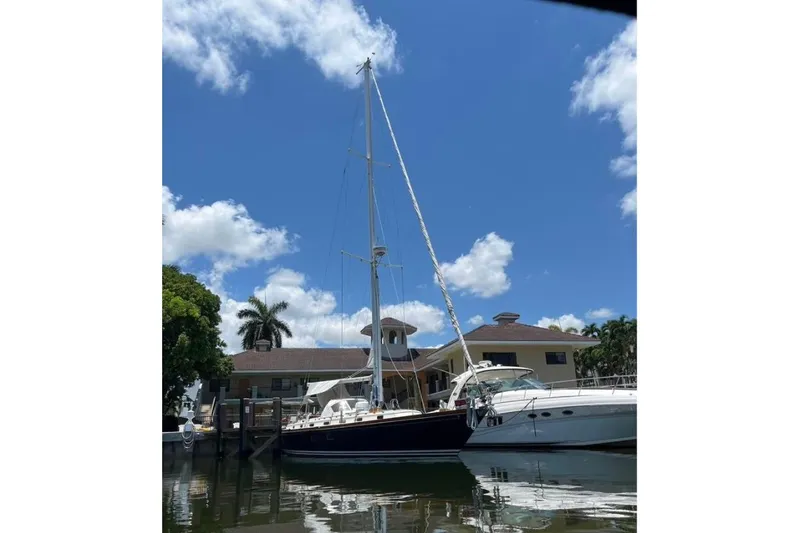 Slide: The Image of 1986 Little Harbor LH46 sailboat docked by a waterfront home under a clear blue sky. - 4