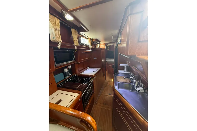 Slide: The Image of 1986 Little Harbor LH46 yacht interior with wooden cabinetry, kitchen appliances, and cozy living space. - 48