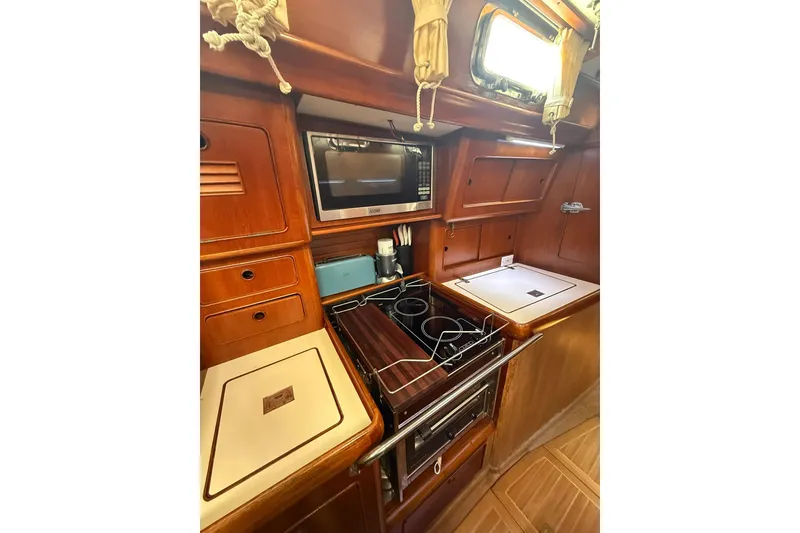 Slide: The Image of 1986 Little Harbor LH46 yacht kitchen with stove, microwave, and wooden cabinetry. - 49