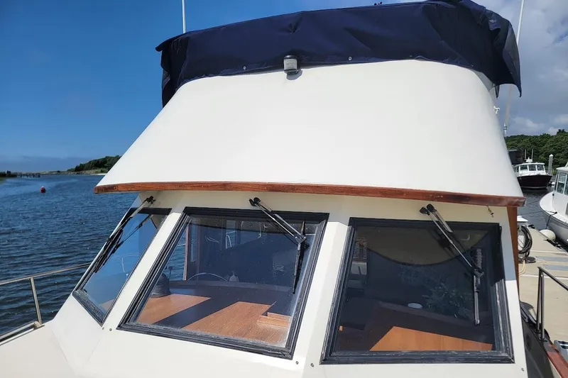 Slide: The Image of 1987 Albin 37 Palm Beach boat with blue canopy docked by the water. - 37