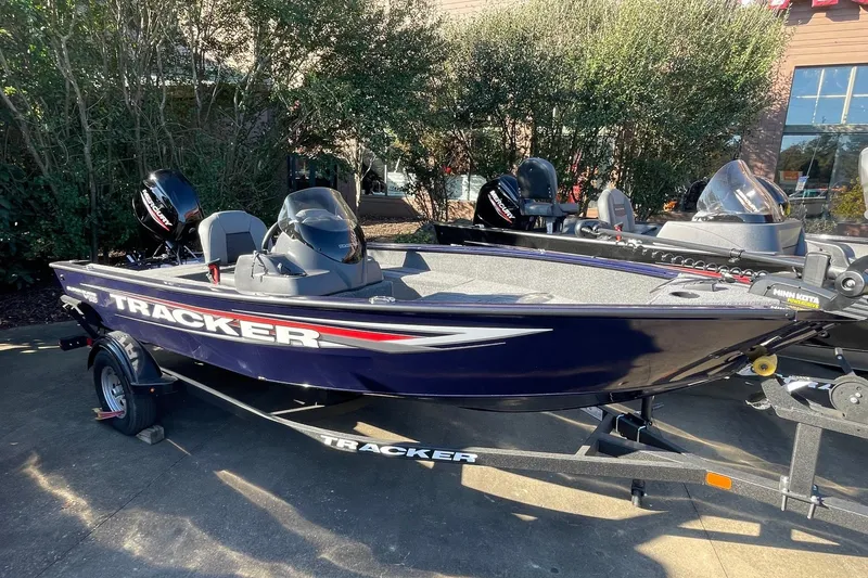 The Image of 2026 Tracker Super Guide V-16 SC fishing boat on trailer, parked outdoors. - 0