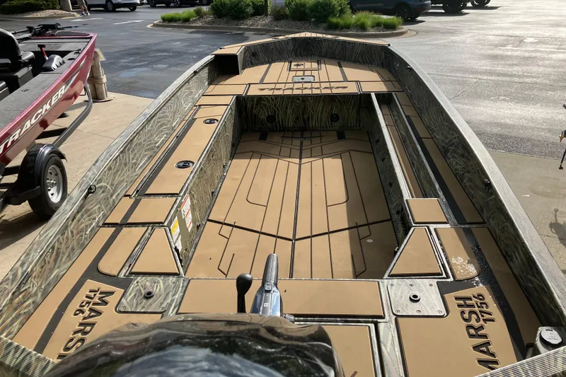Slide: The Image of 2026 Tracker Grizzly 1756 T Marsh boat with camo design, parked outdoors. - 2