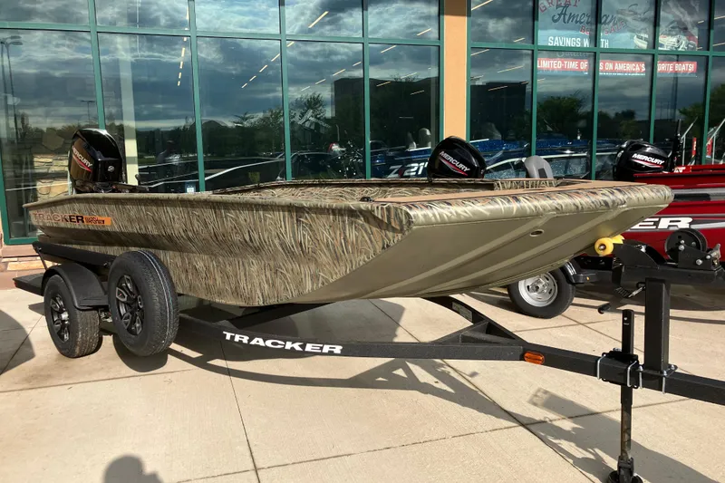 The Image of 2026 Tracker Grizzly 1756 T Marsh boat on trailer, camo design, displayed outdoors. - 0