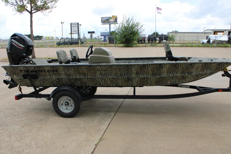 Slide: The Image of 2026 Tracker Grizzly 1754 SC boat on trailer, camo design, parked outdoors. - 4