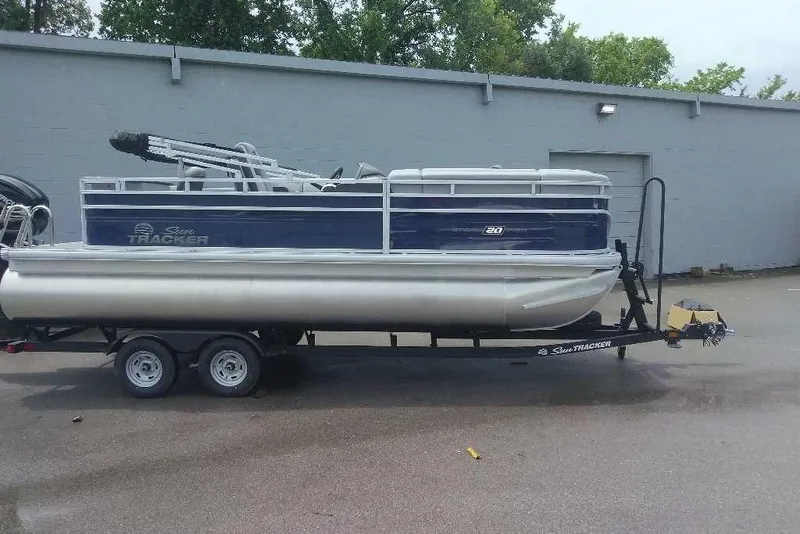 The Image of 2026 Sun Tracker SportFish 20 DLX pontoon boat on trailer, parked outdoors. - 0