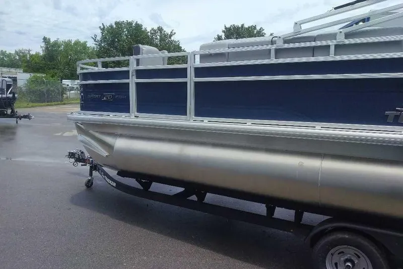 Slide: The Image of 2026 Sun Tracker SportFish 20 DLX pontoon boat on trailer, parked outdoors. - 2