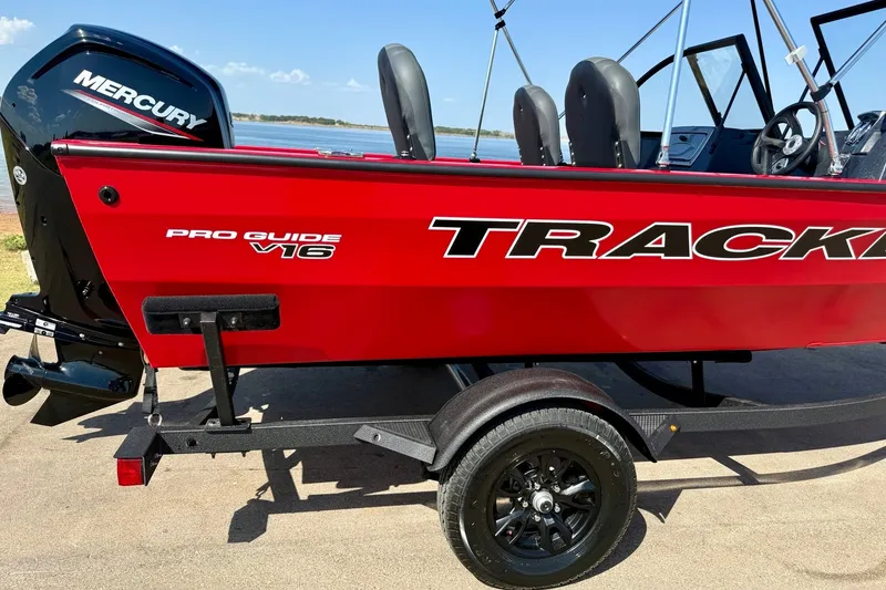 The Image of 2026 Tracker Pro Guide V-16 WT boat with Mercury engine on trailer by the water. - 6
