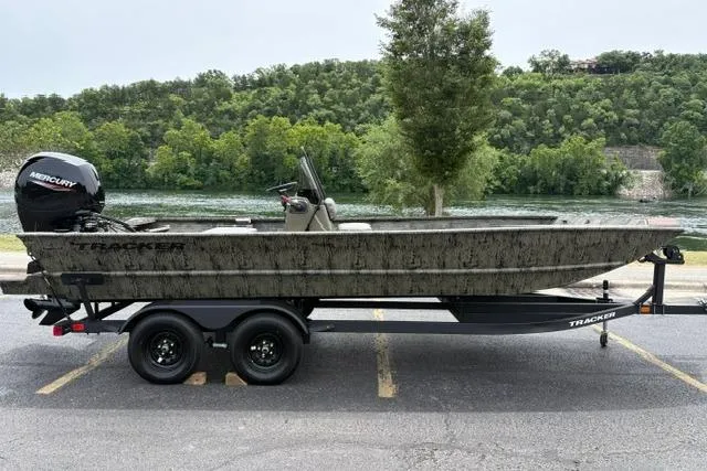The Image of 2026 Tracker Grizzly 2072 CC boat on trailer, parked near a scenic river. - 0