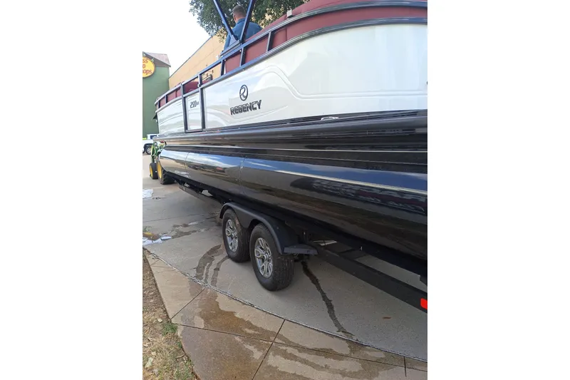 Slide: The Image of 2026 Regency 250 DL3 pontoon boat on a trailer, parked on a driveway. - 15