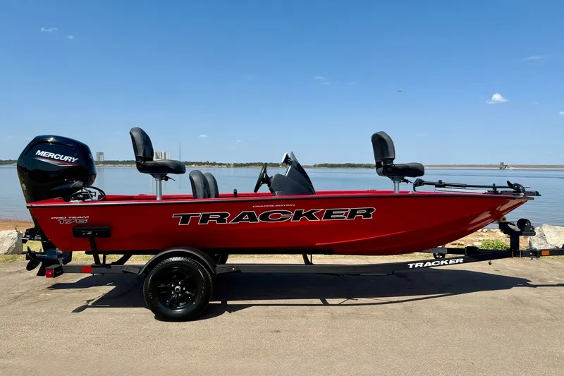 Slide: The Image of Red 2026 Tracker Pro Team 175 Crappie Edition boat by a lake, featuring Mercury engine. - 17