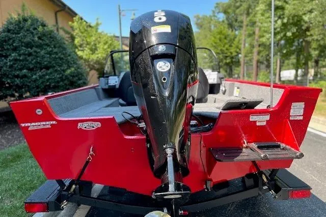 Slide: The Image of 2026 Tracker Pro Guide V-175 Combo boat, red exterior, rear view with motor, parked outdoors. - 4